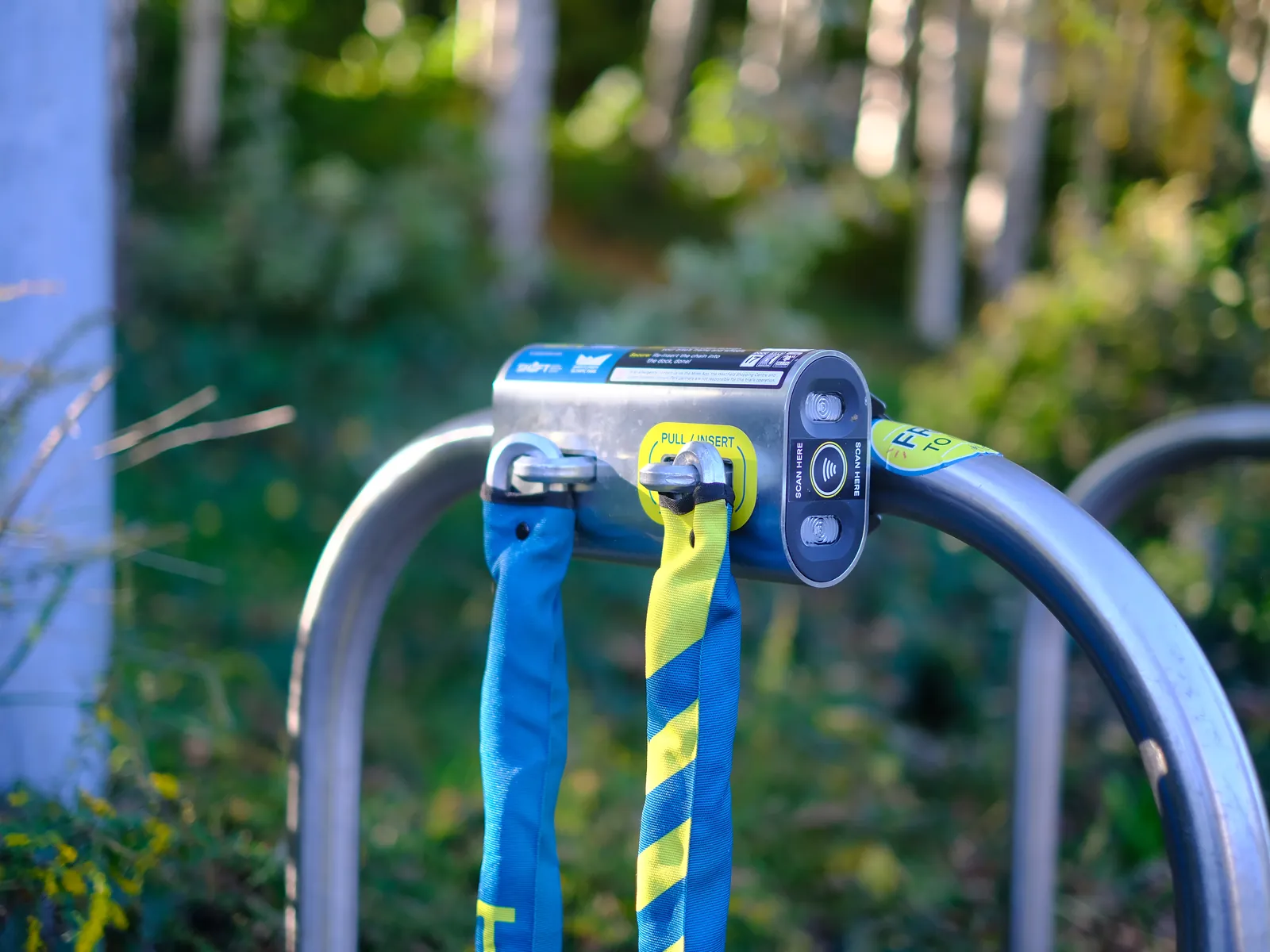 A Mosa dock clamped to a steel bike rack, its blue and yellow chains ready to use.